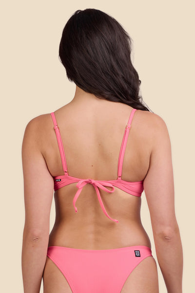 Female model wearing the Women's Hikari Bikini Top in the Tea Rose Ribbed solid, standing in front of a yellow background shown from the back view

|| Size M, Bust 32"  