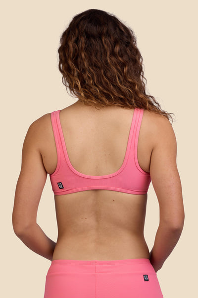 Female model wearing the Women's Larisa Bikini Top in the Tea Rose Ribbed solid, standing in front of a yellow background shown from the back view

|| Size S, Bust 35.5"  