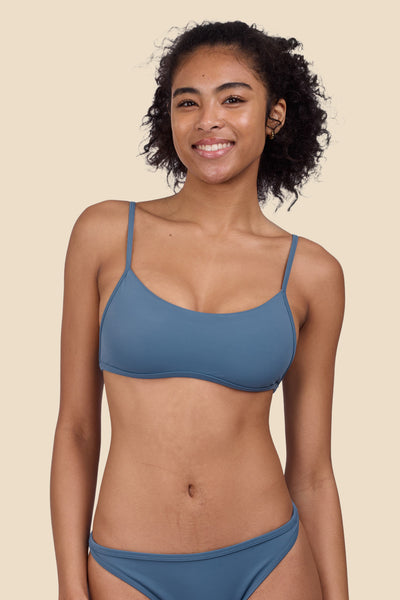 Female model wearing the Women's Lori Bikini Top in the Dolphins solid, standing in front of a yellow background shown from the front view


