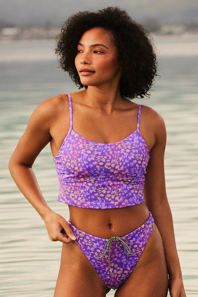 Female model wearing the Women's Luca Tankini Top in the Jellybean print, standing in front of a beach shown from the front view