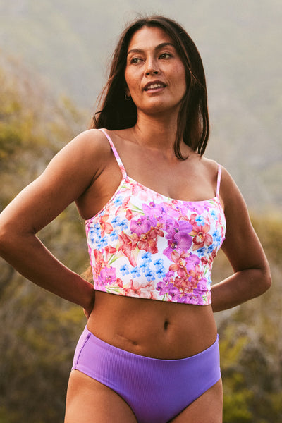 Female model wearing the Women's Luca Tankini Top in the Orchids Ribbed print, standing in front of a green background shown from the front view
