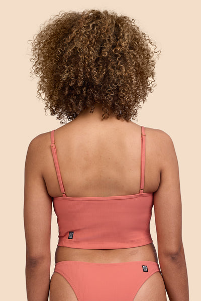Female model wearing the Women's Luca Tankini Top in the Serrano Ribbed solid, standing in front of a yellow background, shown from the back view

|| Size S, Bust 32.5" 