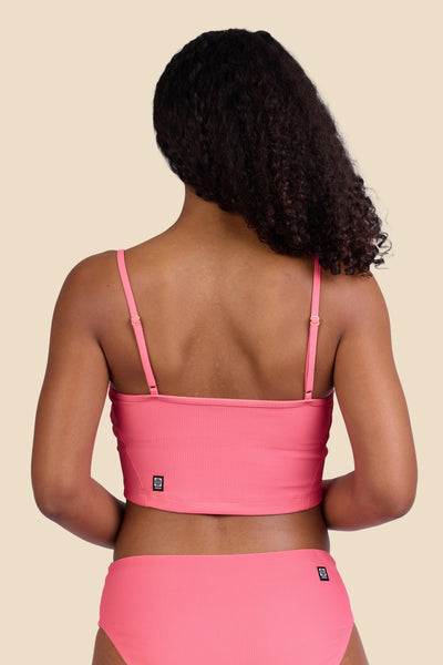 Female model wearing the Women's Luca Bikini Top in the Tea Rose Ribbed solid, standing in front of a yellow background shown from the back view

|| Size S, Bust 32"  