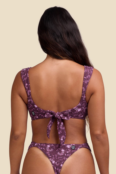 Female model wearing the Women's Lyra Bikini Top in the Bondi Blossom print, standing in front of a yellow background shown from the back view

|| Size S, Bust 34"  