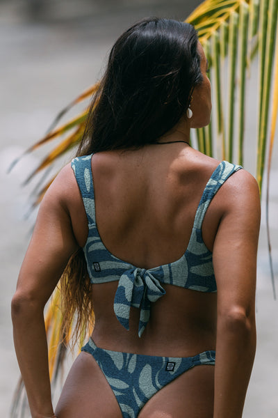 Female model wearing the Women's Lyra Bikini Top in the Sumatra print, standing in front of a green background shown from the back view

|| Size S, Bust 34"  