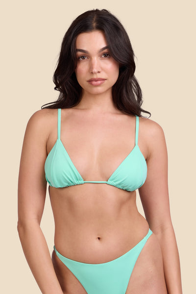 Female model wearing the Women's Margie Bikini Top in the Mint Tulip solid, standing in front of a yellow background shown from the front view

|| Size M, Bust 32"  
