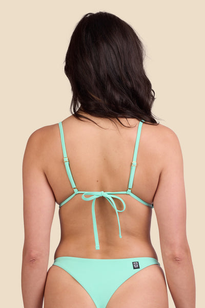 Female model wearing the Women's Margie Bikini Top in the Mint Tulip solid, standing in front of a yellow background shown from the back view

|| Size M, Bust 32"  
