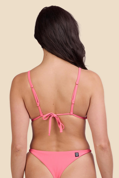 Female model wearing the Women's Margie Bikini Top in the Tea Rose Ribbed solid, standing in front of a yellow background shown from the back view

|| Size M, Bust 32"  