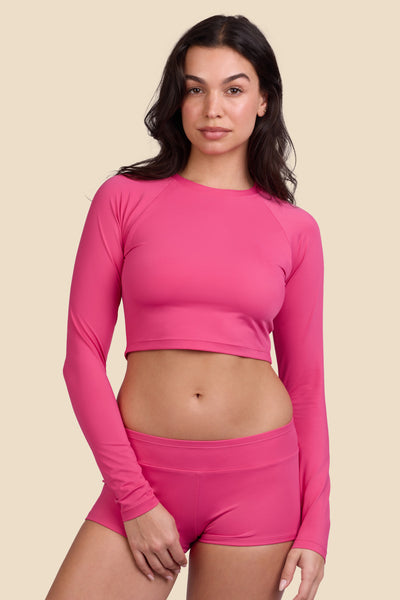 Female model wearing the Women's Moana Rashie in the Berry solid, standing in front of a yellow background shown from the front view

|| Size M, Bust 32"  
