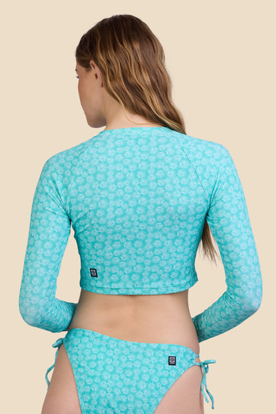 Female model wearing the Women's Moana Rashie in the Clamshell Ribbed print, standing in front of a yellow background shown from the back view

|| Size S, Bust 30.5"  
