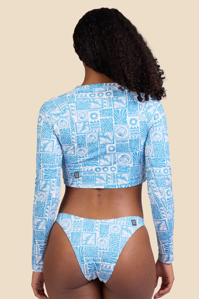Female model wearing the Women's in the Moana Rashguard in the Swell print, standing in front of a yellow background shown from the back view

|| Size S, Bust 32"