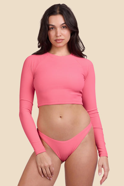 Female model wearing the Women's Moana Rashguard in the Tea Rose Ribbed solid, standing in front of a yellow background shown from the front view

|| Size M, Bust 32"  