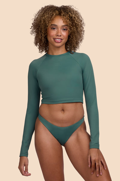 Female model wearing the Women's Moana Long Sleeve Rashgard in the Zucchini solid, standing in front of a yellow background shown from the front view

|| Size S, Bust 32.5"  