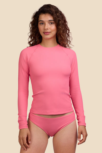 Female model wearing the Women's Noonan Rashguard in the Tea Rose Ribbed solid, standing in front of a yellow background shown from the front view

|| Size S, Bust 35.5"  