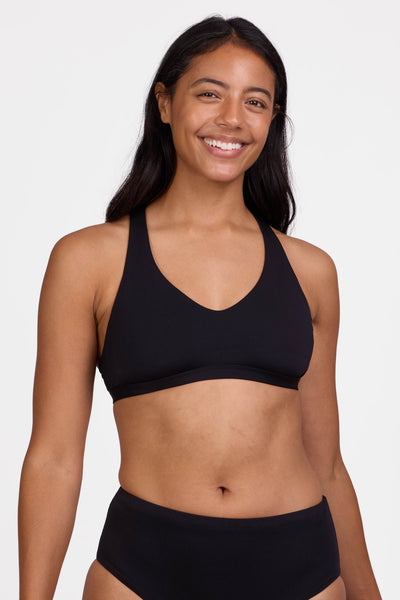 Female model wearing the Women's Eloise Bikini Top in the Black solid, standing in front of a grey background shown from the front view


|| Size L, Bust 36"