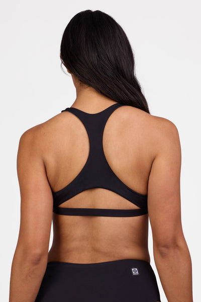 Female model wearing the Women's Eloise Bikini Top in the Black solid, standing in front of a grey background shown from the back view


|| Size L, Bust 36"