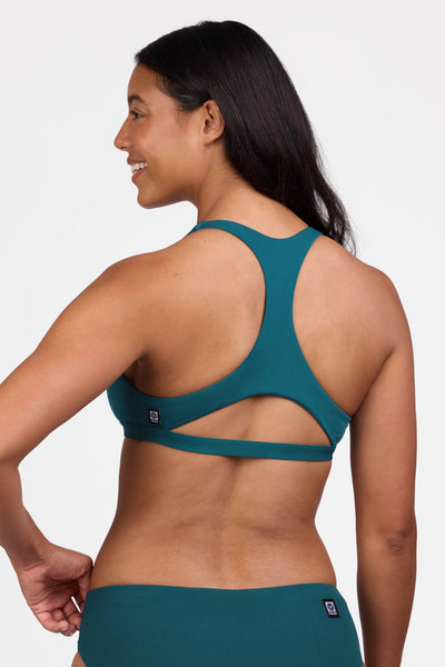 Female model wearing the Women's Eloise    D+ Bikini Top in the Peacock solid, standing in front of a grey background shown from the back view


|| Size L, Bust 36"