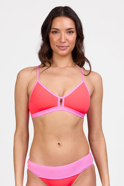 Female model wearing the Women's Eviana Bikini Top in the Neon Guava contrast, standing in front of a grey background shown from the front view

|| Size L, Bust 34"  
