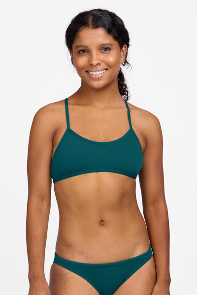 Female model wearing the Women's Ryan Bikini Top in the Peacock solid, standing in front of a grey background shown from the front view

|| Size S, Bust 32.5"