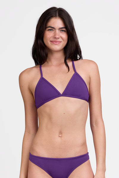 Female model wearing the Women's Triangle Bikini Top in the Grape solid, standing in front of a grey background shown from the front view

|| Size S, Bust 31"