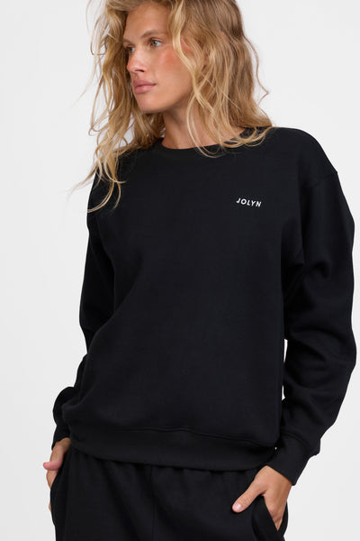 Female model wearing the Women's Ellison Crewneck in the Black solid, standing in front of a grey background, shown from the front view

|| Size S, Bust 31.5"  
