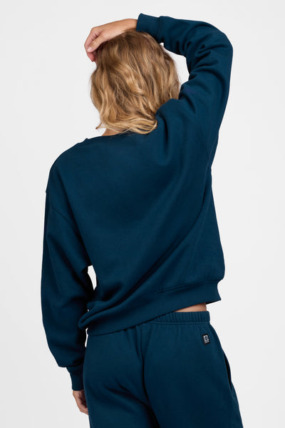 Female model wearing the Women's Ellison Crewneck in the Indigo solid, standing in front of a grey background, shown from the back view

|| Size M, Bust 31.5"  