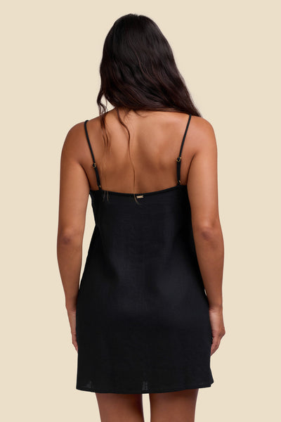 Female model wearing the Women's Nina Dress in the Black solid, standing in front of a yellow background shown from the back view

|| Size S, Height 5'4"  