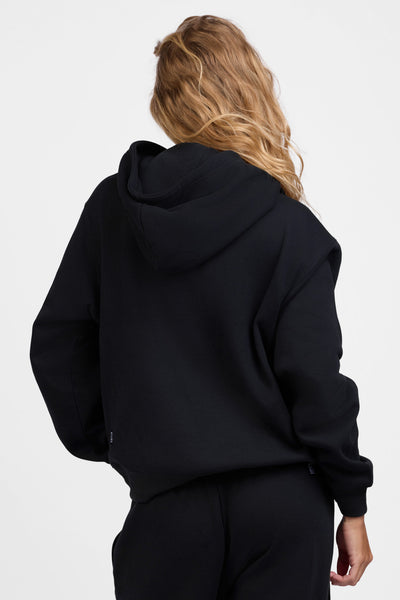 Female model wearing the Women's Lana Hoodie in the Black solid, standing in front of a grey background, shown from the back view

|| Size S, Bust 31.5"  