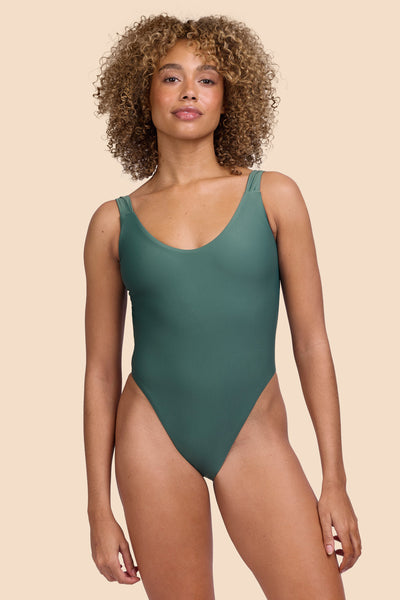 Female model wearing the Womens Jiro Surf Onesie in the Zucchini solid, standing in front of a yellow background shown from the front view

|| Size S, Torso 57.5"  