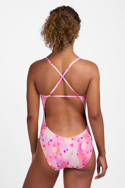 Female model wearing the Women’s Brandon One Piece Swimsuit in the Berry Zest print, standing in front of a grey background, shown from back view. 