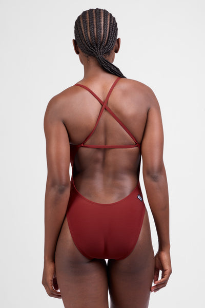 Female model wearing the Women’s Brandon One Piece in the Paprika solid, standing in front of a grey background, shown from back view. 

