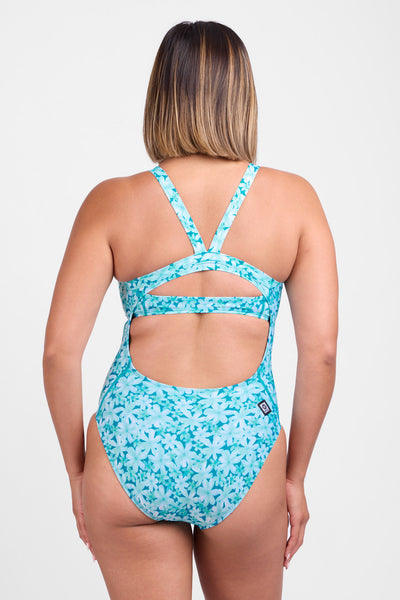 Female model wearing the Women's Caroline One Piece Swimsuit in the Rosabelle print, standing in front of a grey background, shown from the back view. 