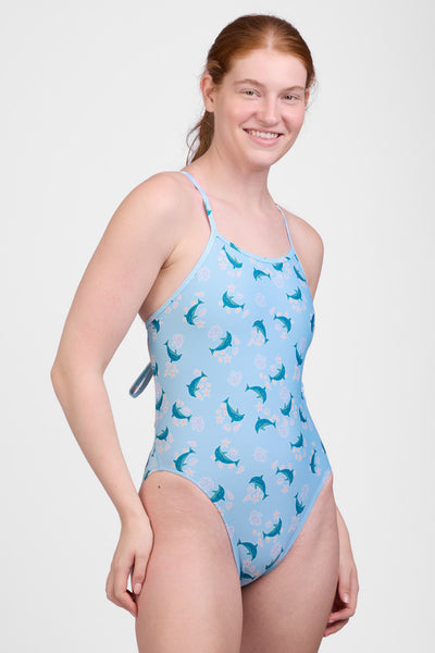 Female model wearing the Women’s Jackson One Piece Swimsuit in the Dolphrenz print, standing in front of a grey background, shown from front view. 
