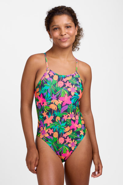 Female model wearing the Women’s Jackson One Piece Swimsuit in the Luminosity print, standing in front of a grey background, shown from front view. 
