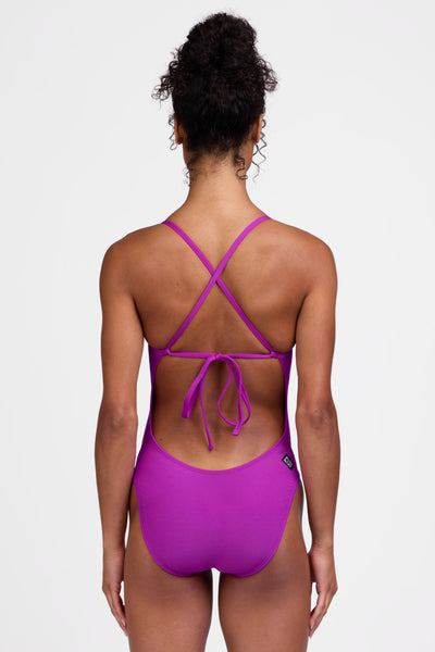 Female model wearing the Women's Jackson One Piece Swimsuit in the Solar Plum solid, standing in front of a grey background shown from the back view

|| Size 28, Torso 56"  
