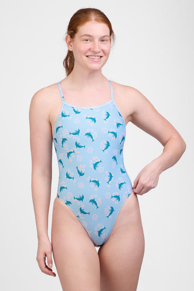 Female model wearing the Women’s Perry One Piece Swimsuit in the Dolphrenz print, standing in front of a grey background, shown from front view. 