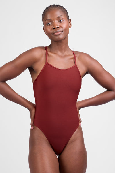 Female model wearing the Women’s Perry One Piece in the Paprika solid, standing in front of a grey background, shown from front view. 
