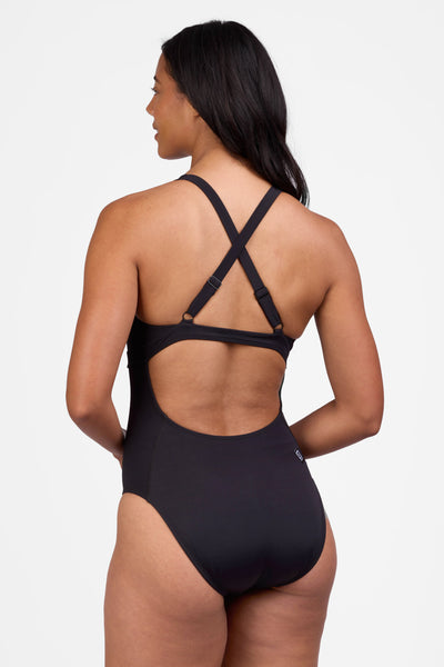 Female model wearing the Women's Toni One Piece Swimsuit in the Black solid, standing in front of a grey background shown from the side view

|| Size 30, Height 5'9"