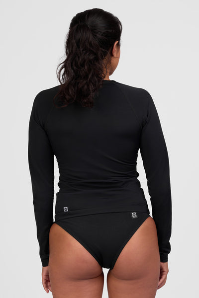 Female model wearing the Women's Daniela Rashguard in the Black solid, standing in front of a grey background shown from the back view

|| Size S, Bust 34"  