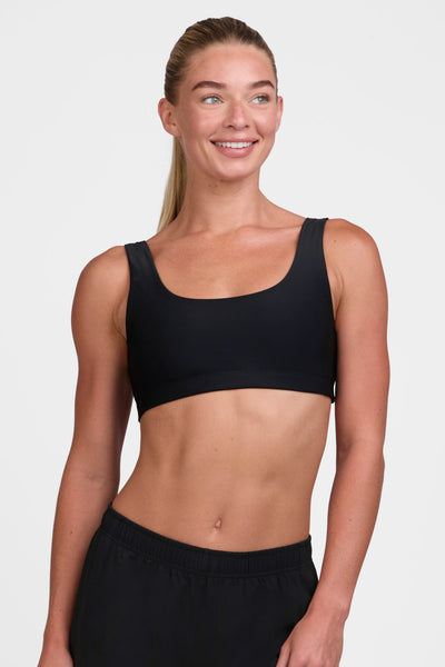 Female model wearing the Women's Arabella Sports Bra in the Black solid, standing in front of a grey background shown from the front view 

|| Size S, Bust 33"