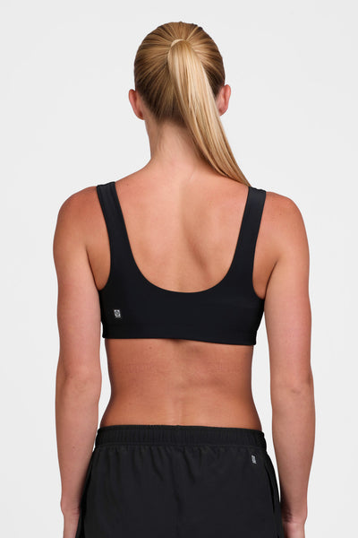 Female model wearing the Women's Arabella Sports Bra in the Black solid, standing in front of a grey background shown from the back view 

|| Size S, Bust 33"