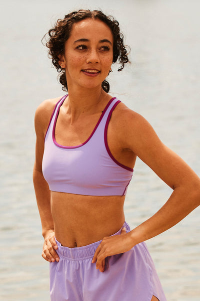 Female model wearing the Women's Molly Sports Bra in the Lilac Haze contrast, standing in front of a grey background shown from the front view 

|| Size XS, Bust 30.5"