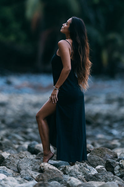 Female model wearing the Women's Lydia Dress in the Black solid, standing in front of a green background shown from the side view

|| Size S, Height 5'4"  
