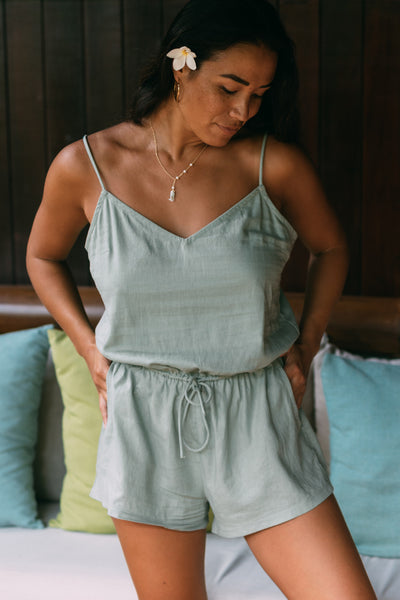 Female model wearing the Women's Naia Cover up Romper in the Algae solid, standing in front of a brown background shown from the front view

|| Size S, Height 5'4"  