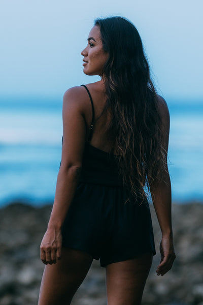 Female model wearing the Women's Naia Romper in the Black solid, standing in front of a blue background shown from the back view

|| Size S, Height 5'4"  