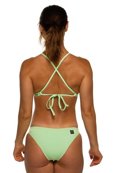 Female model wearing the Women's Europe Bikini Bottoms in Mint solid, standing in front of a grey background, shown from the back view 